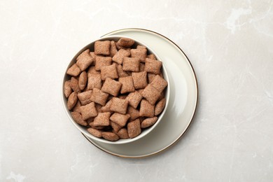 Sweet crispy corn pads in bowl on light marble table, top view