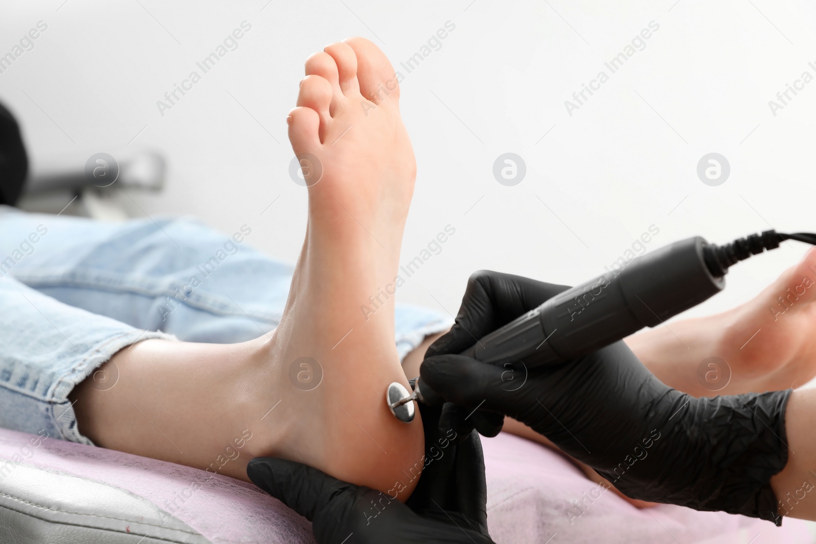 Photo of Professional master making hardware pedicure for client in beauty salon, closeup