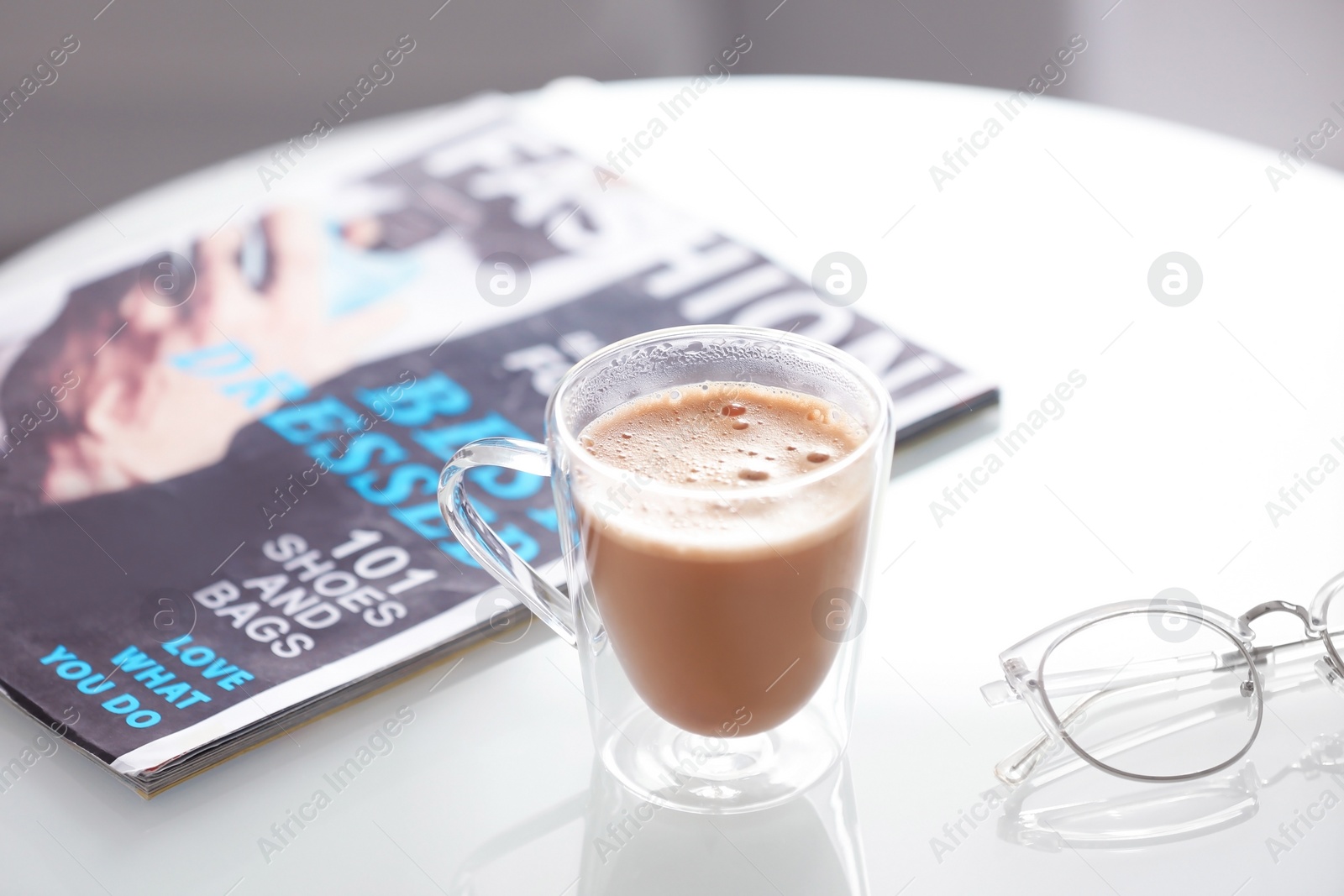 Photo of Cup of aromatic coffee and magazine on table