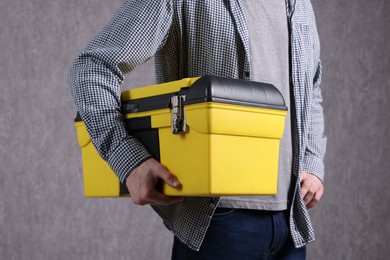 Young man with tool box on grey background, closeup