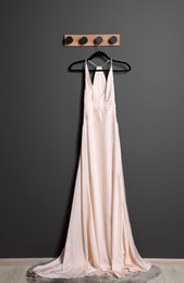 Photo of Beautiful white women's party dress on hanger near grey wall. Stylish trendy clothes for high school prom