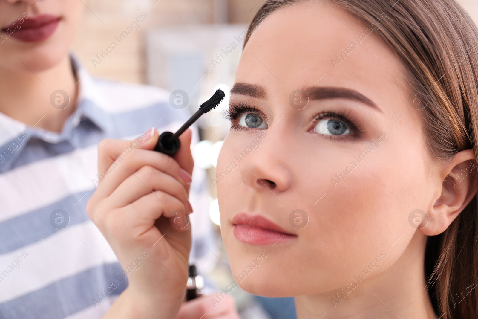 Photo of Professional visage artist applying makeup on woman's face in salon, closeup