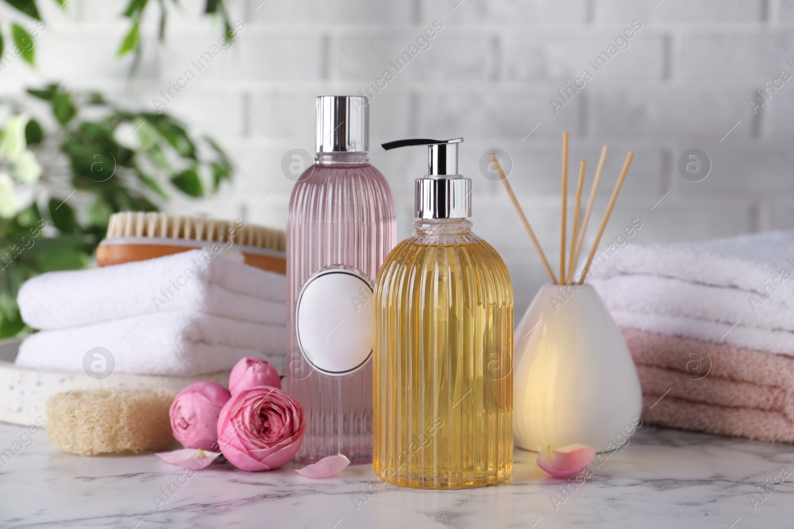 Photo of Stylish dispenser with liquid soap and other bathroom amenities on white marble table