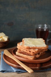 Photo of Tasty toasts with butter served on wooden table