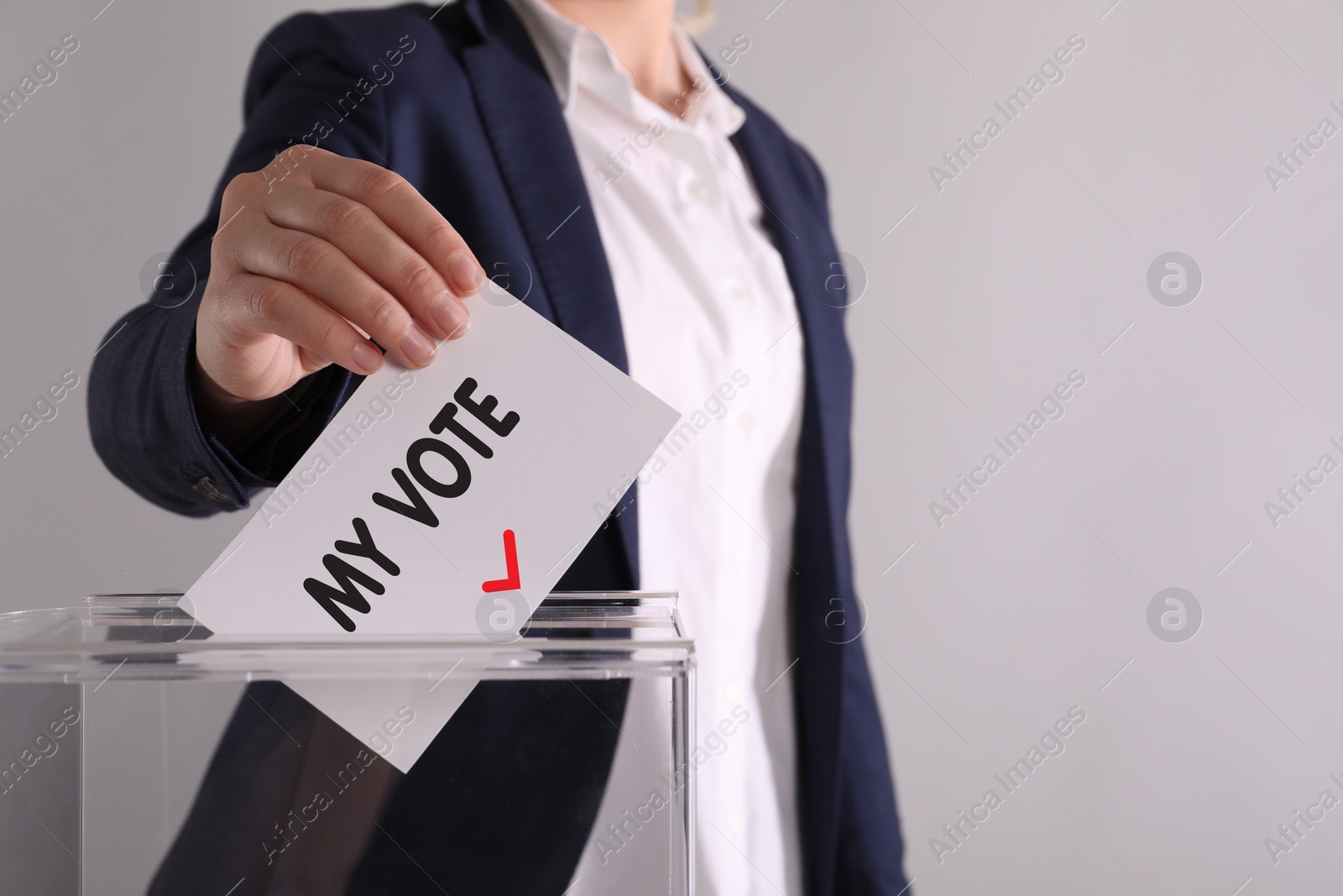 Image of Woman putting paper with text My Vote and tick into ballot box on light grey background