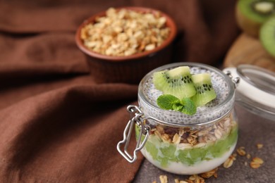 Photo of Delicious dessert with kiwi and chia seeds on brown table, closeup. Space for text