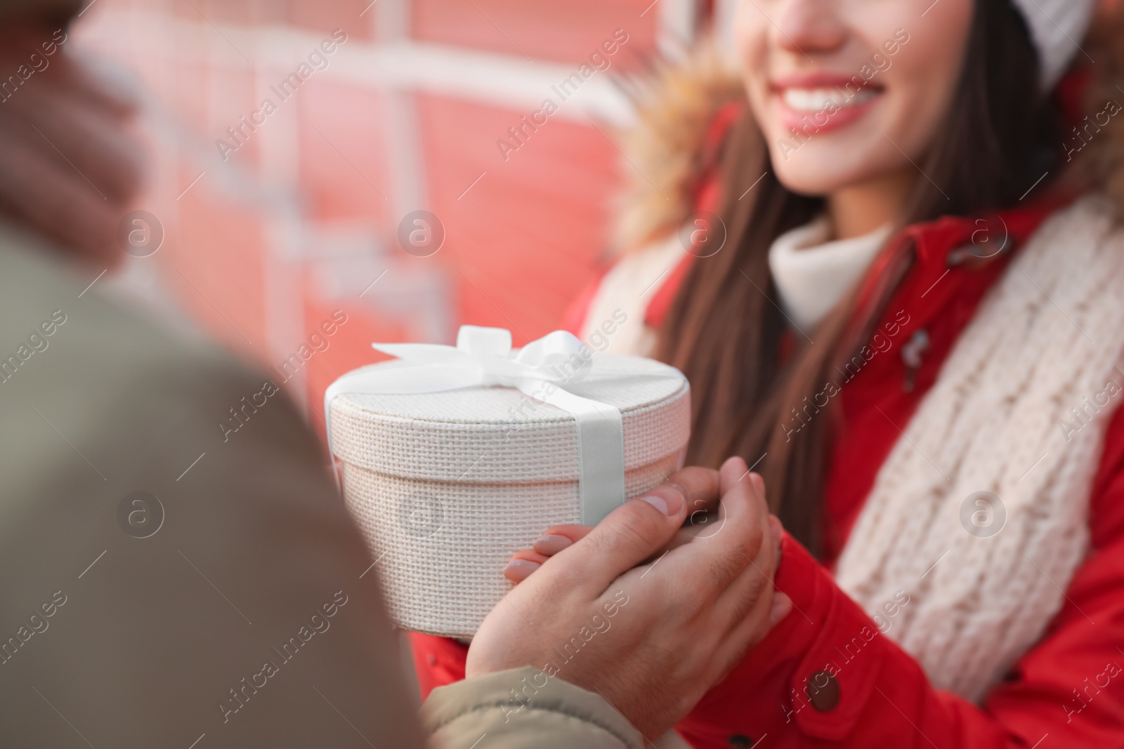 Photo of Happy young couple with gift box at winter fair, closeup. Christmas celebration