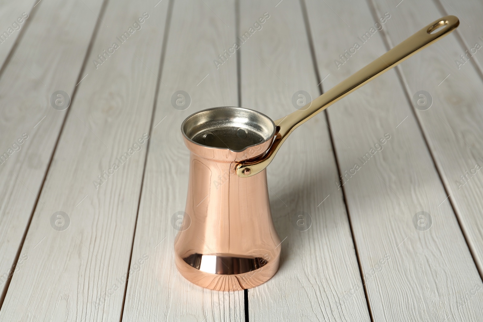 Photo of Copper turkish coffee pot on white wooden table