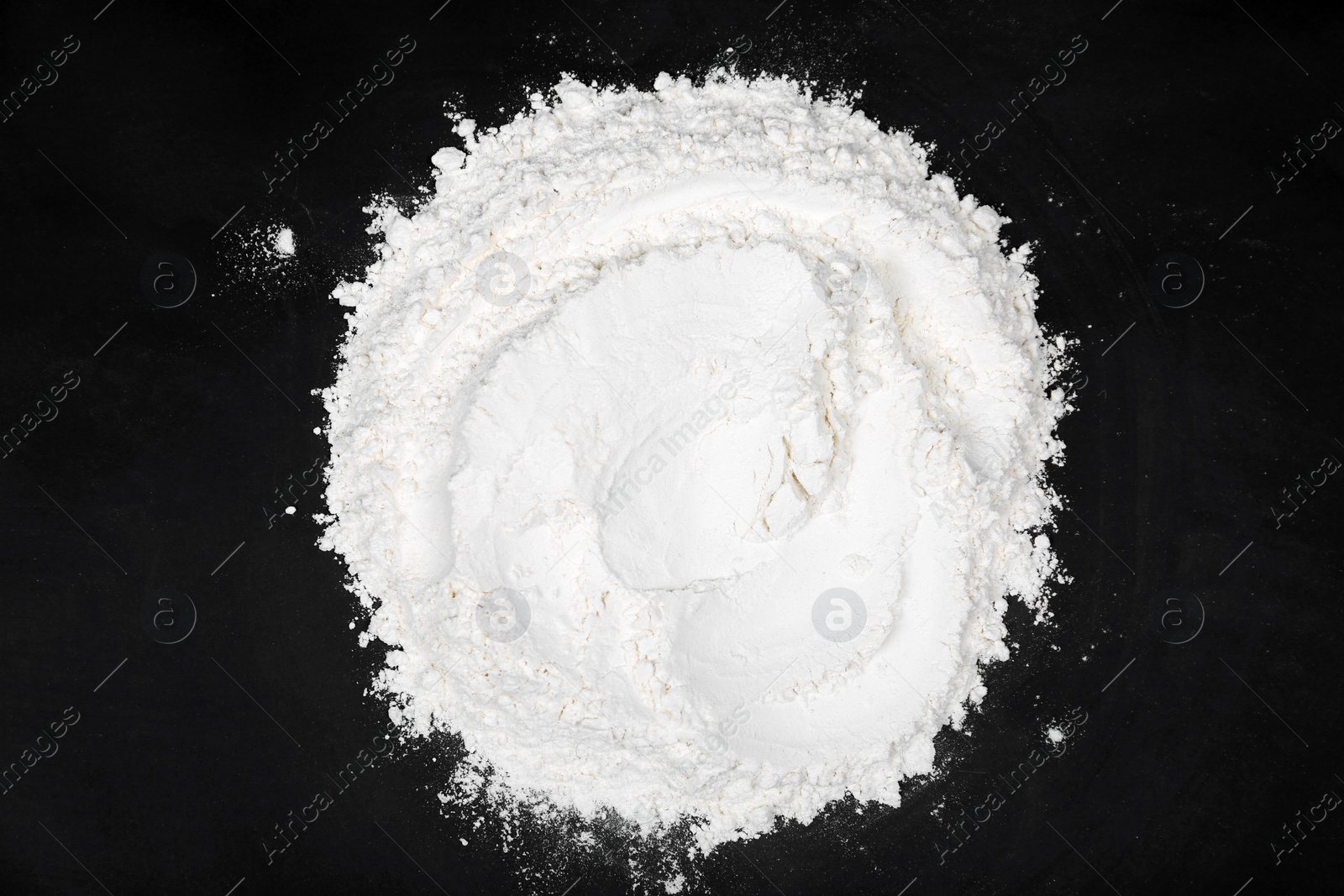 Photo of Pile of flour on black table, top view