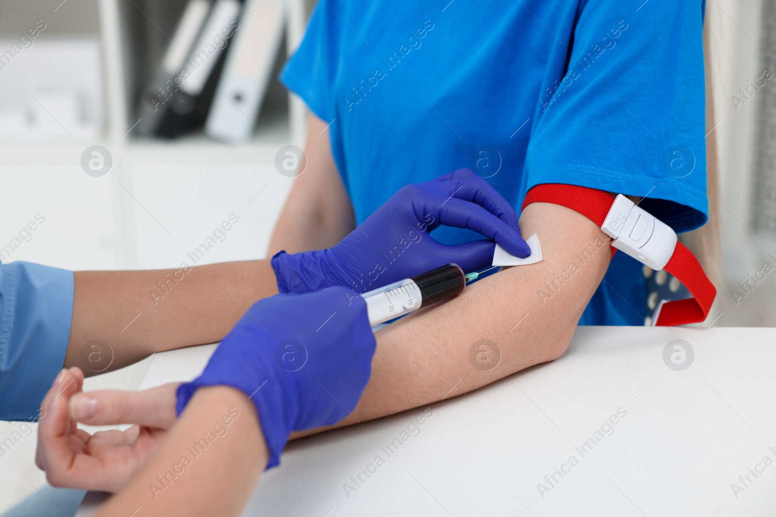 Photo of Laboratory testing. Doctor taking blood sample from patient at white table in hospital, closeup