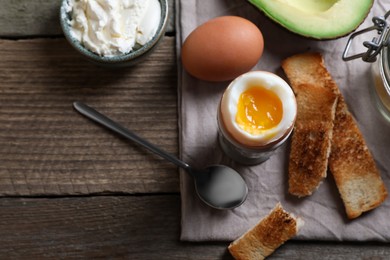 Photo of Soft boiled egg served for breakfast on wooden table, flat lay