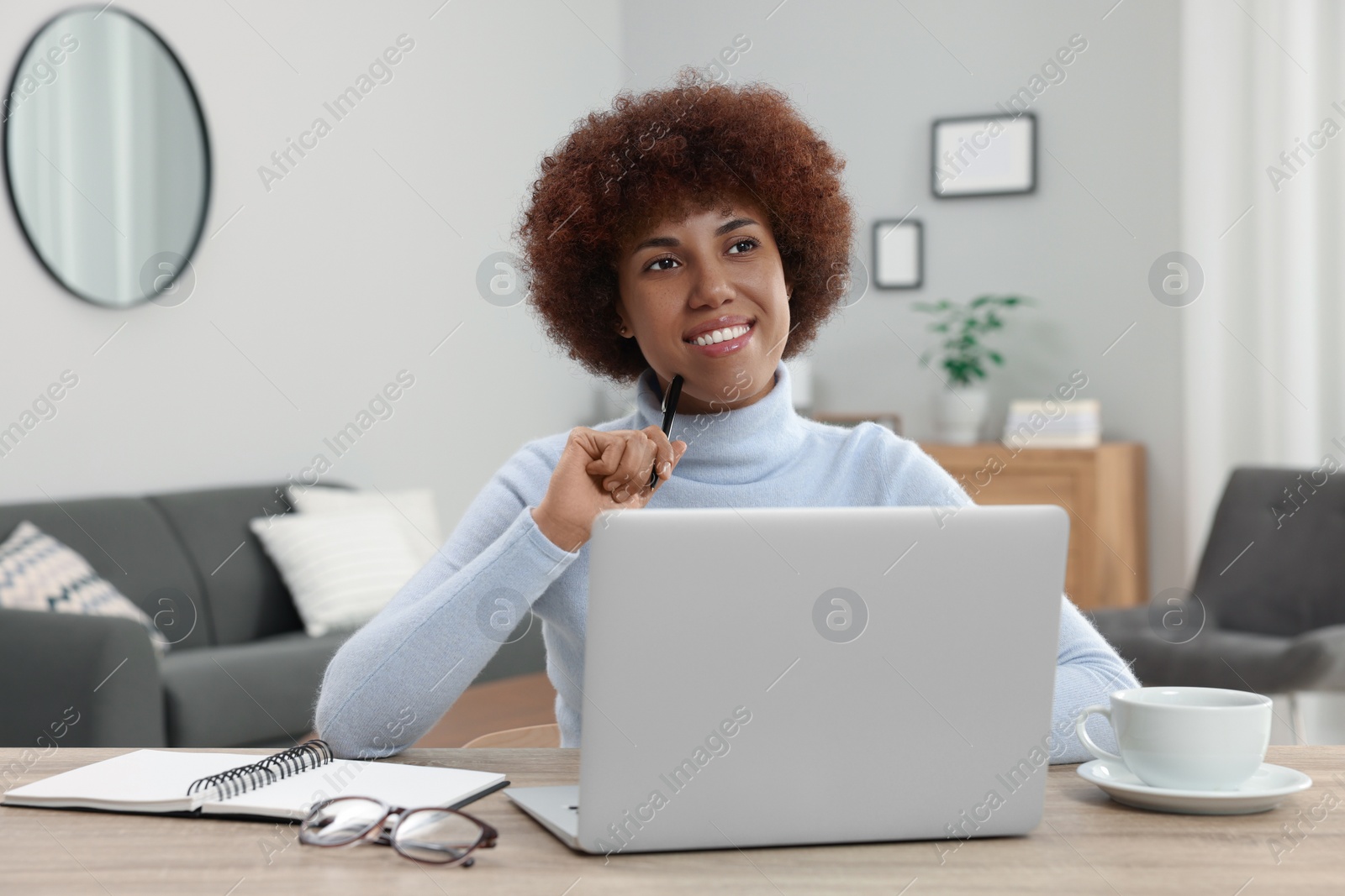 Photo of Beautiful young woman using laptop at wooden desk in room