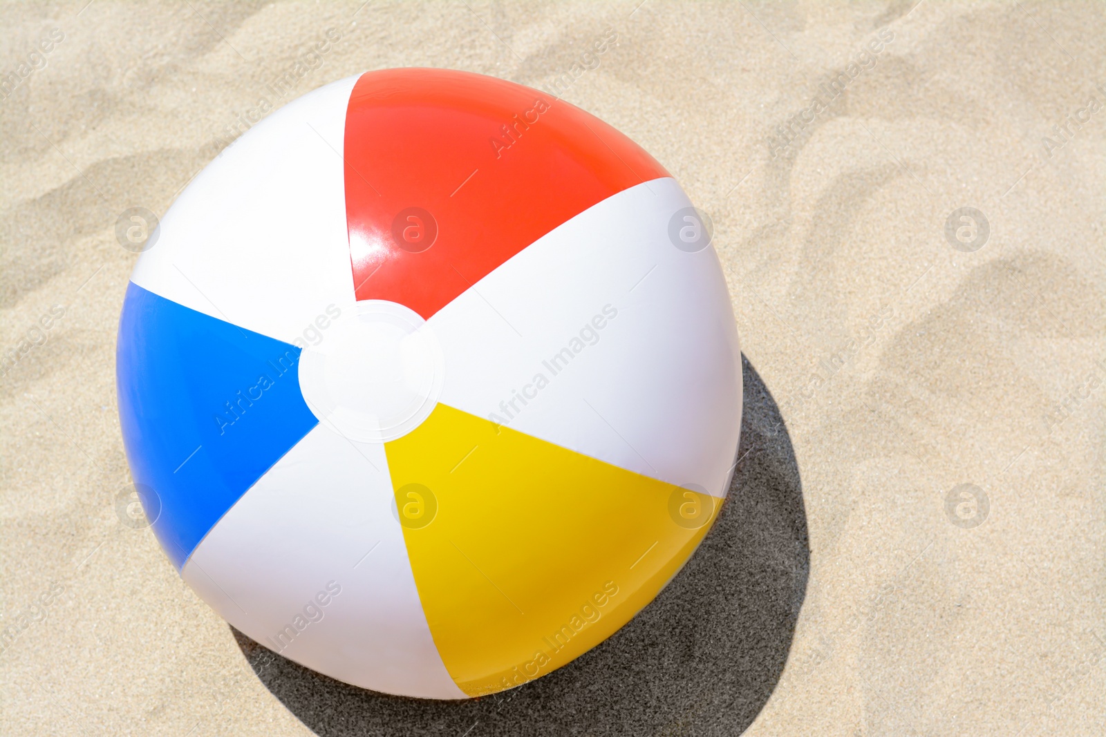 Photo of Colorful beach ball on sand, top view