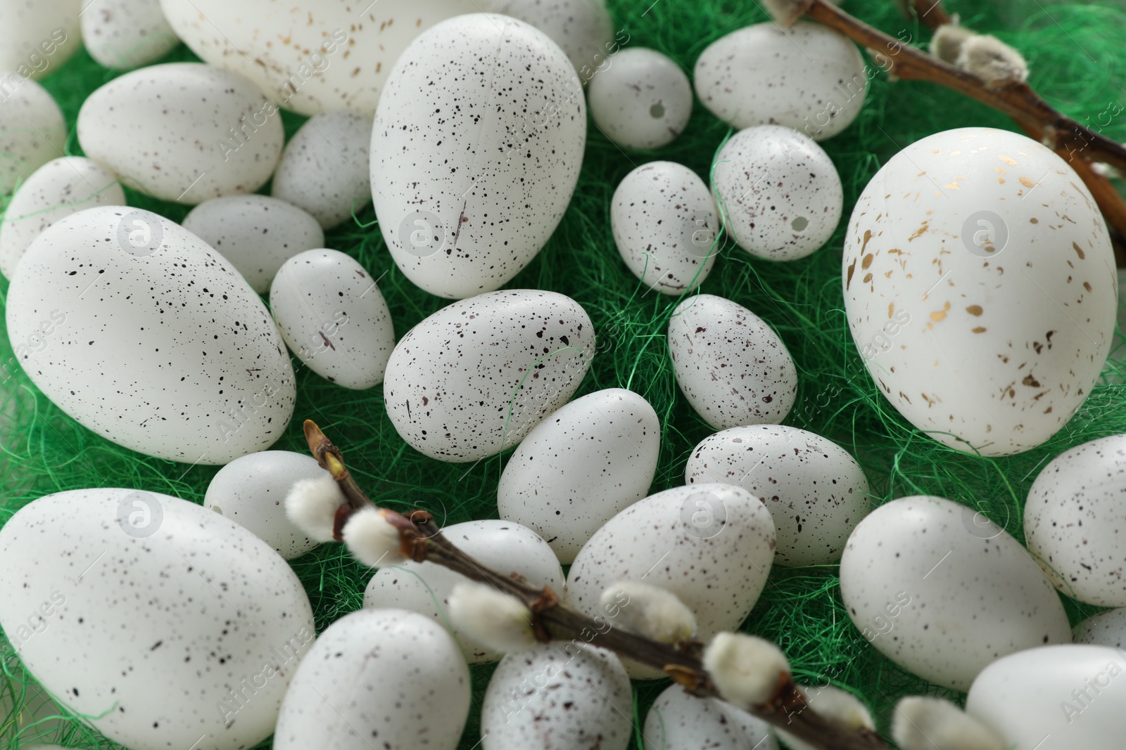 Photo of Many beautifully painted Easter eggs and pussy willow branches on green background, closeup