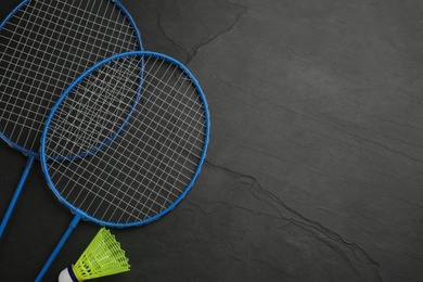 Photo of Rackets and shuttlecock on black background, flat lay with space for text. Badminton equipment