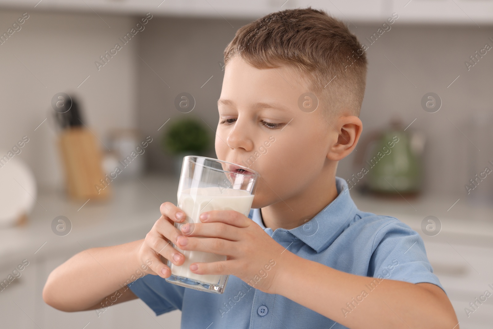 Photo of Cute boy drinking fresh milk from glass indoors