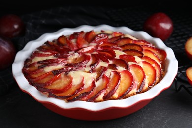 Photo of Delicious cake with plums on black table, closeup