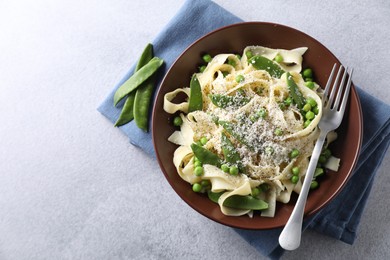 Delicious pasta with green peas and cheese served on grey table. Space for text