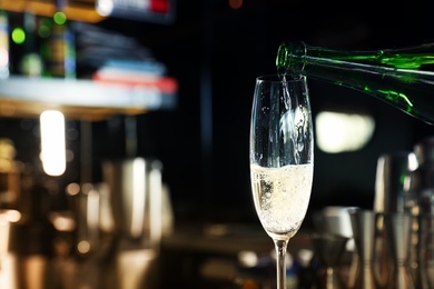Photo of Pouring champagne from bottle into glass in bar. Space for text