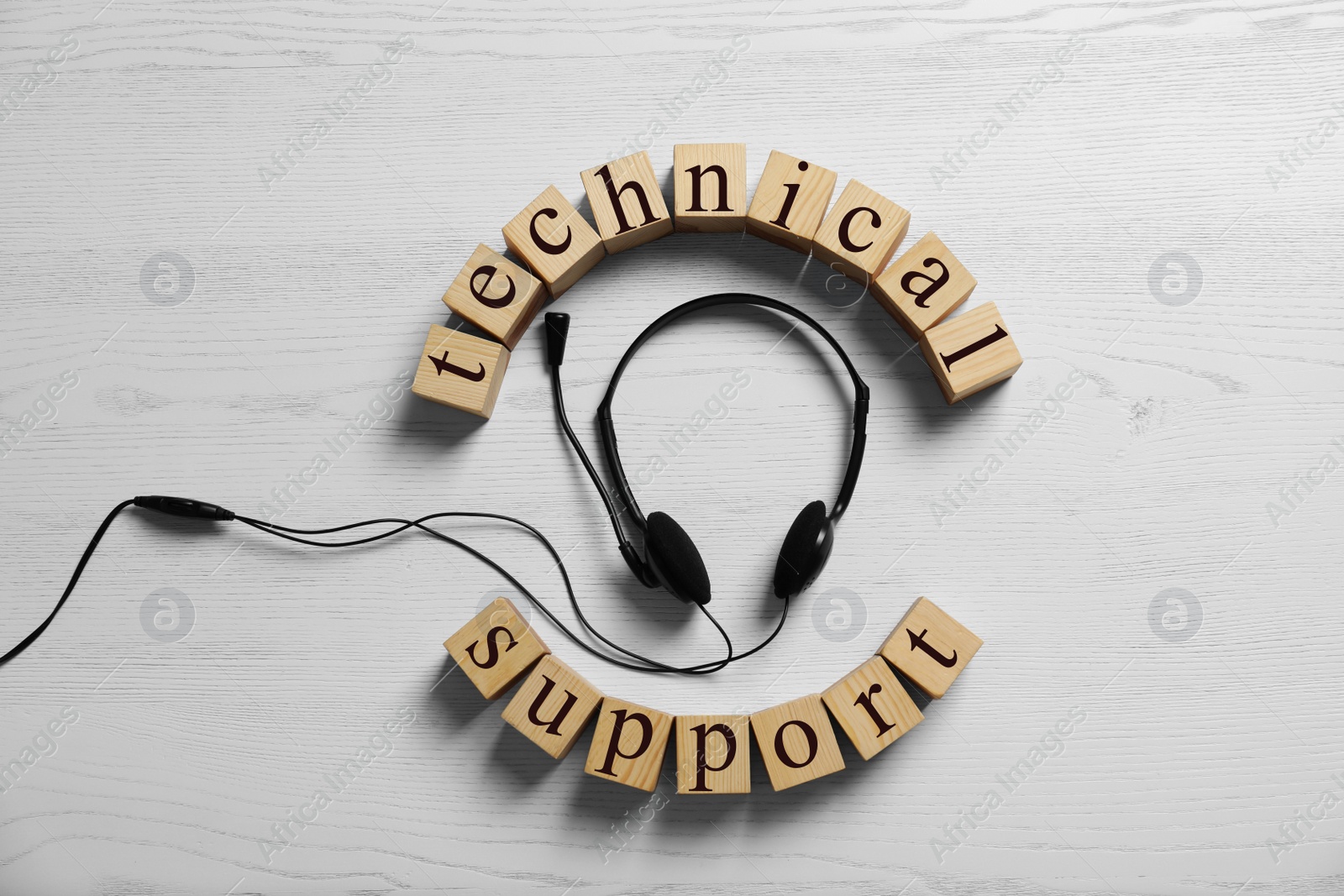 Photo of Flat lay composition with words TECHNICAL SUPPORT and headset on wooden background