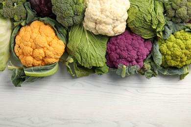 Different cabbages on wooden table, top view. Healthy food