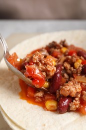 Photo of Tasty chili con carne with tortillas on table, closeup