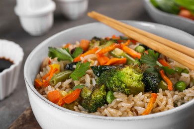 Photo of Tasty fried rice with vegetables in bowl, closeup