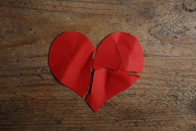 Torn paper heart on wooden background, top view. Relationship problems concept