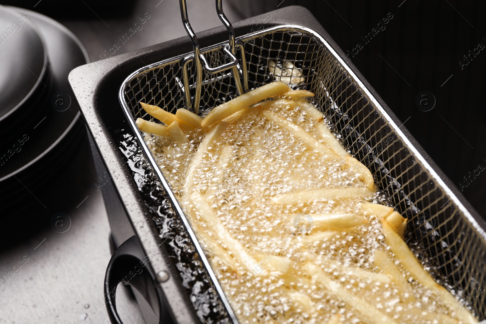 Photo of Cooking delicious french fries in hot oil, closeup