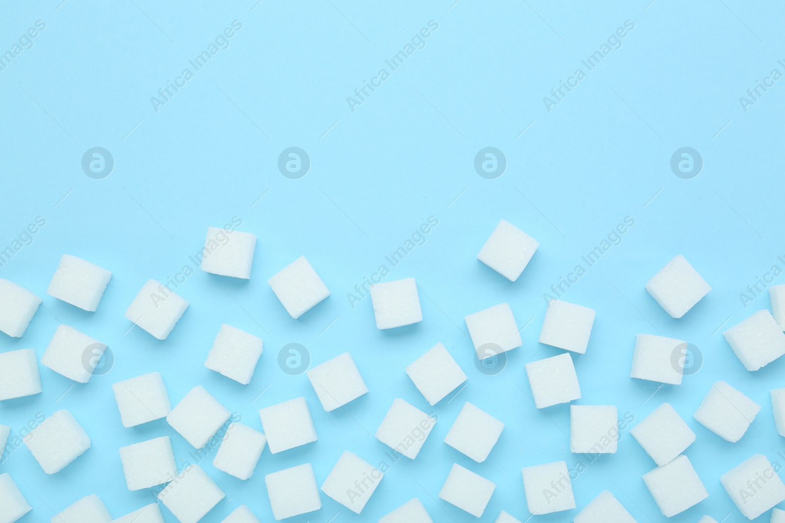 Photo of White sugar cubes on light blue background, top view. Space for text