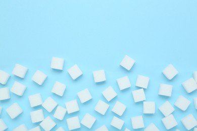 White sugar cubes on light blue background, top view. Space for text