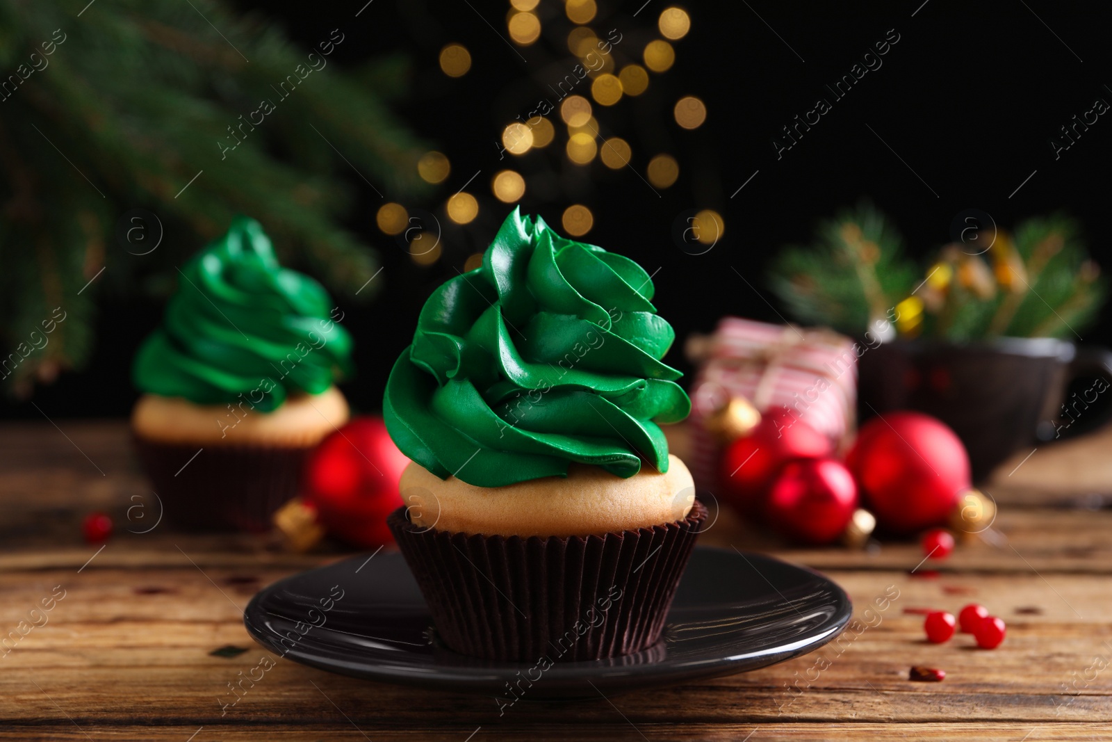 Photo of Delicious cupcake with green cream and Christmas decor on wooden table