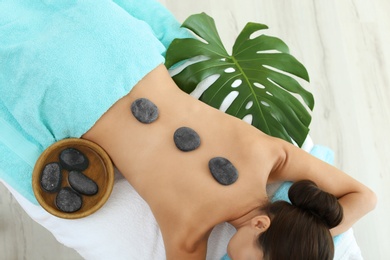 Photo of Beautiful young woman getting hot stone massage in spa salon, top view