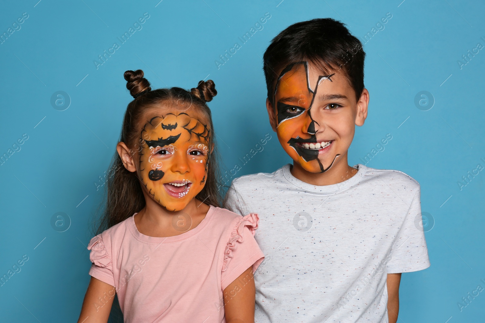 Photo of Cute little children with face painting on blue background