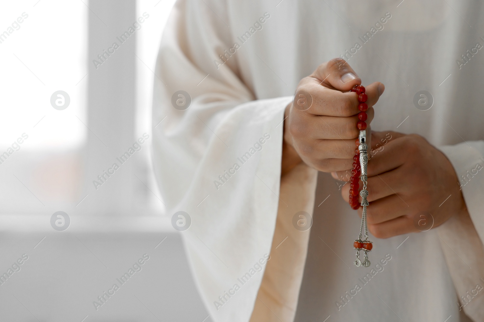 Photo of Muslim man with misbaha indoors, closeup. Space for text