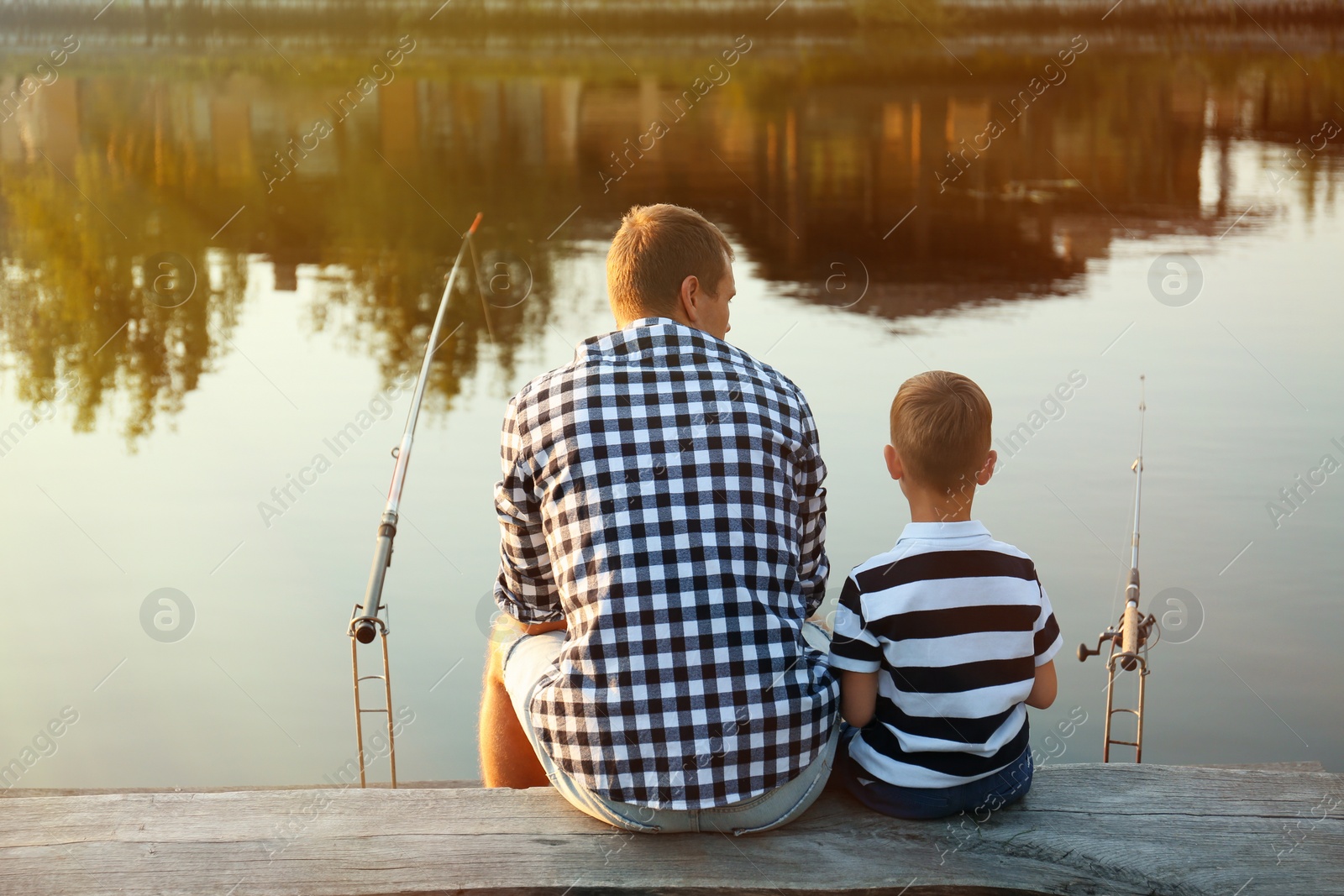 Photo of Dad and son fishing together on sunny day