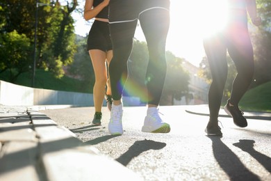 Group of people running outdoors on sunny day, closeup