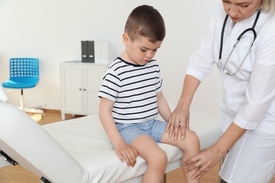 Photo of Doctor examining little patient with knee problem in clinic