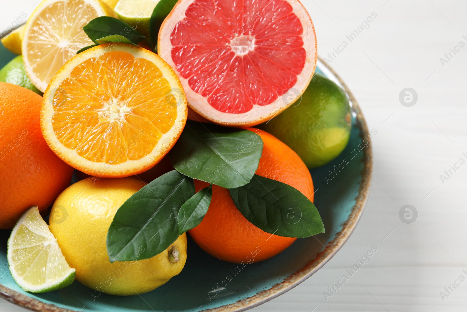 Photo of Different cut and whole citrus fruits on white wooden table, closeup. Space for text