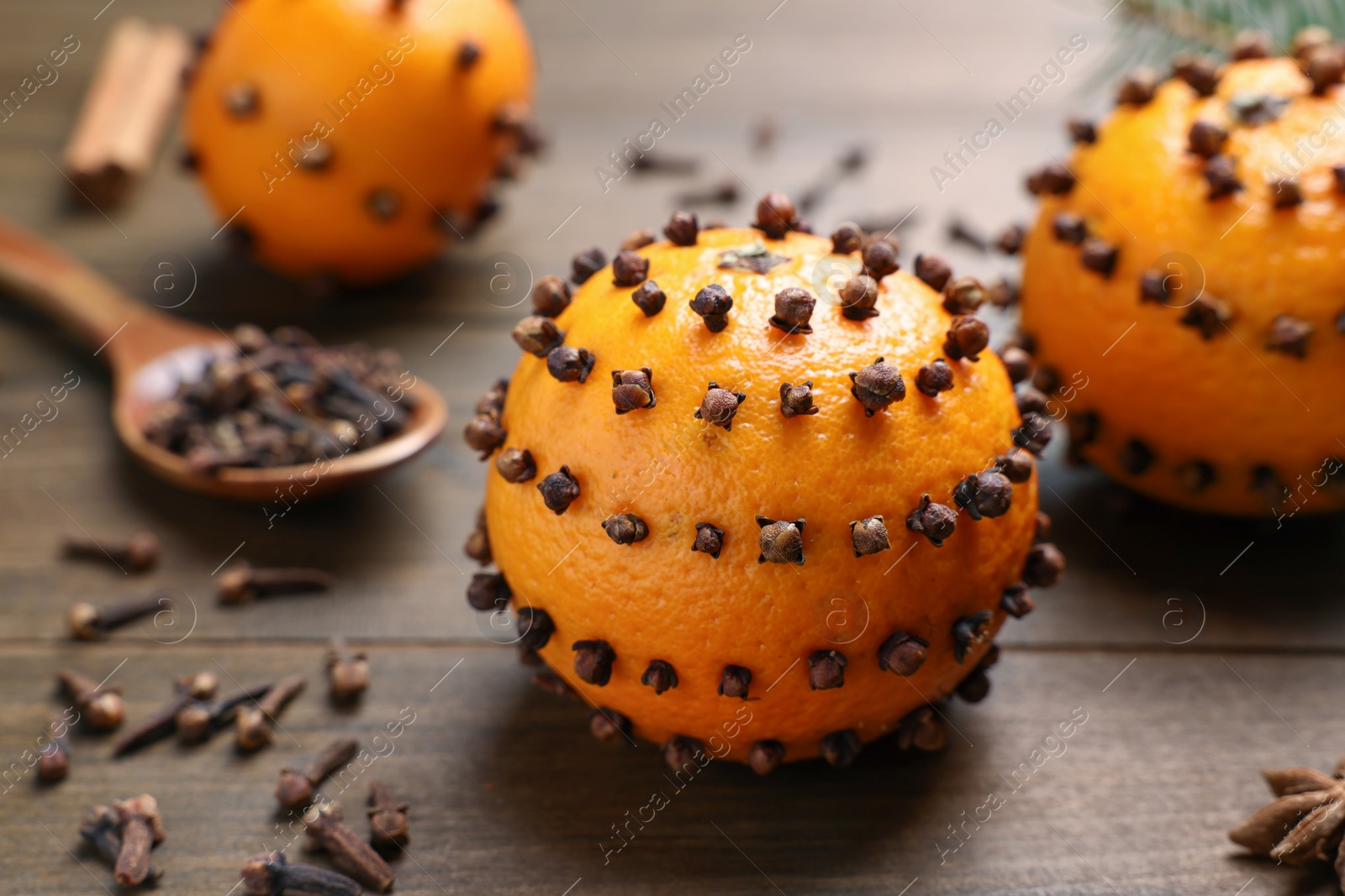 Photo of Pomander balls made of tangerines with cloves on wooden table, closeup