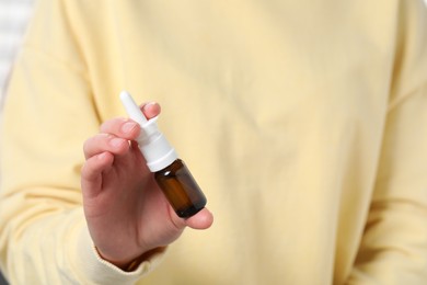 Photo of Woman holding nasal spray indoors, closeup view