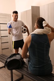 Photo of Handsome athletic men talking in locker room