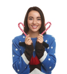 Young woman in Christmas sweater holding candy canes on white background