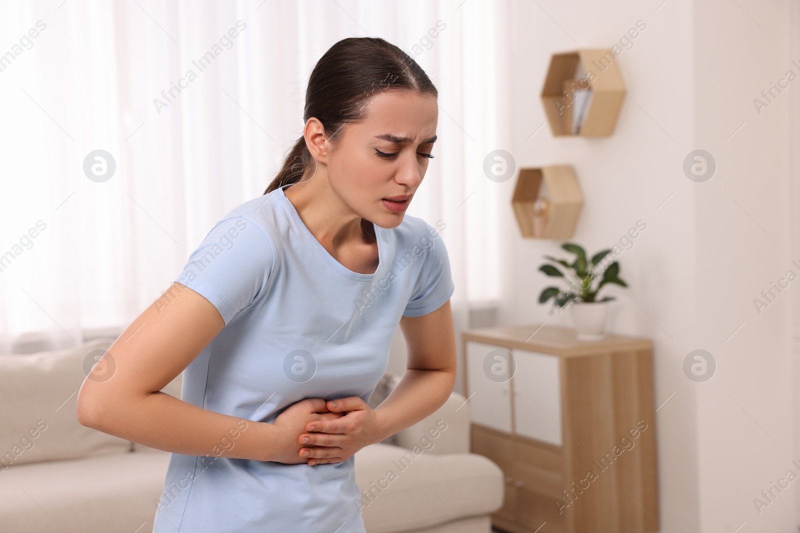 Photo of Woman suffering from abdominal pain at home. Unhealthy stomach
