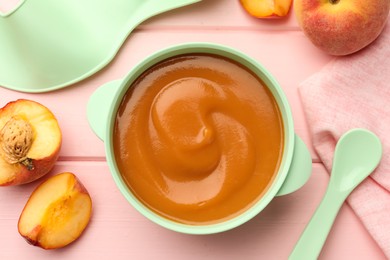 Photo of Bowl with tasty pureed baby food and ingredients on pink wooden table, flat lay