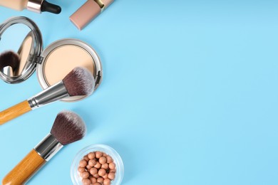 Flat lay composition with makeup brushes on light blue background, space for text