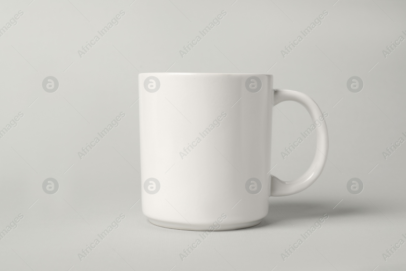 Photo of One white ceramic mug on light grey background