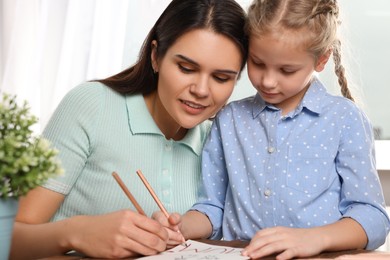 Cute little girl with her mother making beautiful greeting card at home