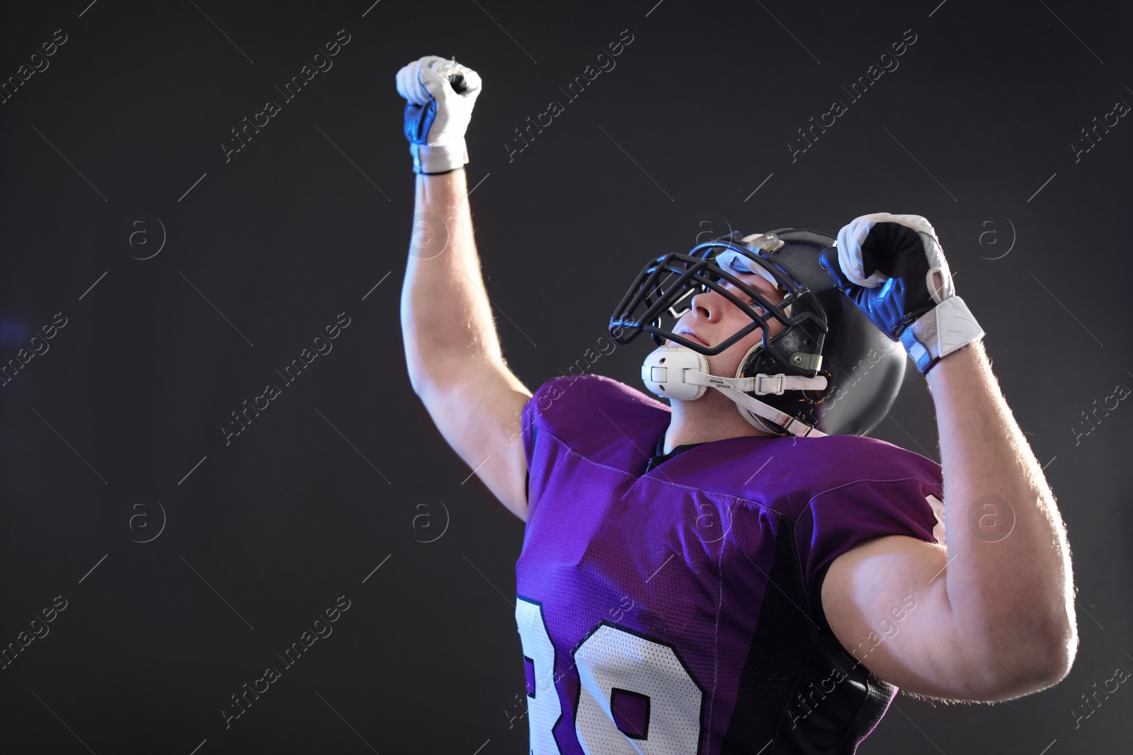 Photo of American football player wearing uniform on dark background. Space for text