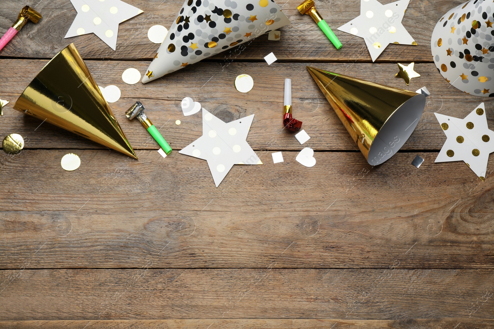 Photo of Colorful party hats and other festive items on wooden table, flat lay. Space for text